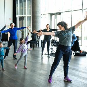 A group of people dance in a bright room.