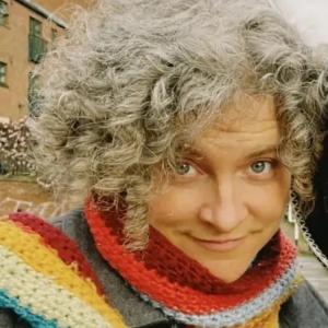 A woman with curly grey hair and a colorful scarf