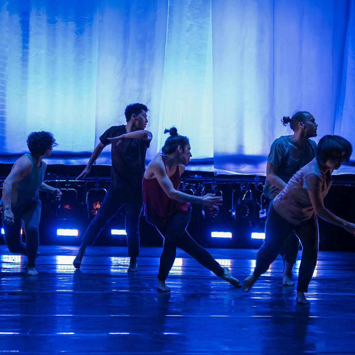 Dancers in blue light looking backwards.