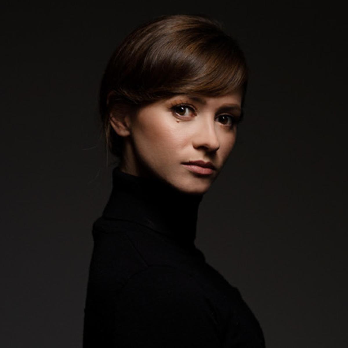 A photo of a woman in a black turtleneck with dark brown hair.