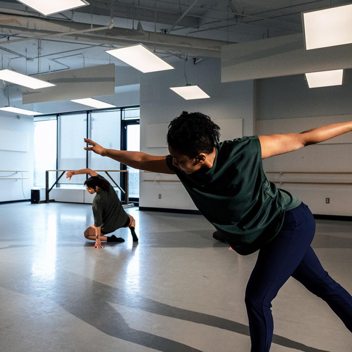 Three people dance in a bright studio space
