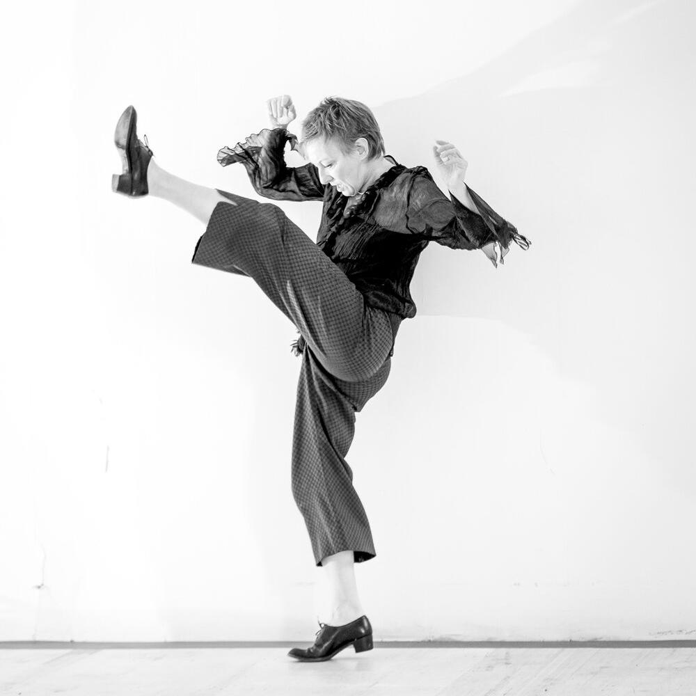 A woman dances, kicking one leg high