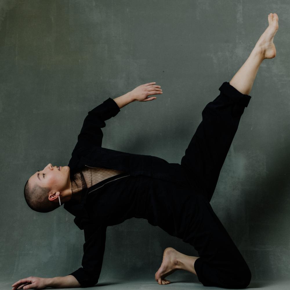 A dancer leans on the floor with one leg in the air. 
