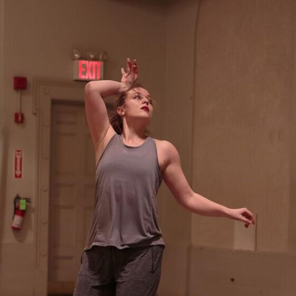 A woman dancing in grey clothing.