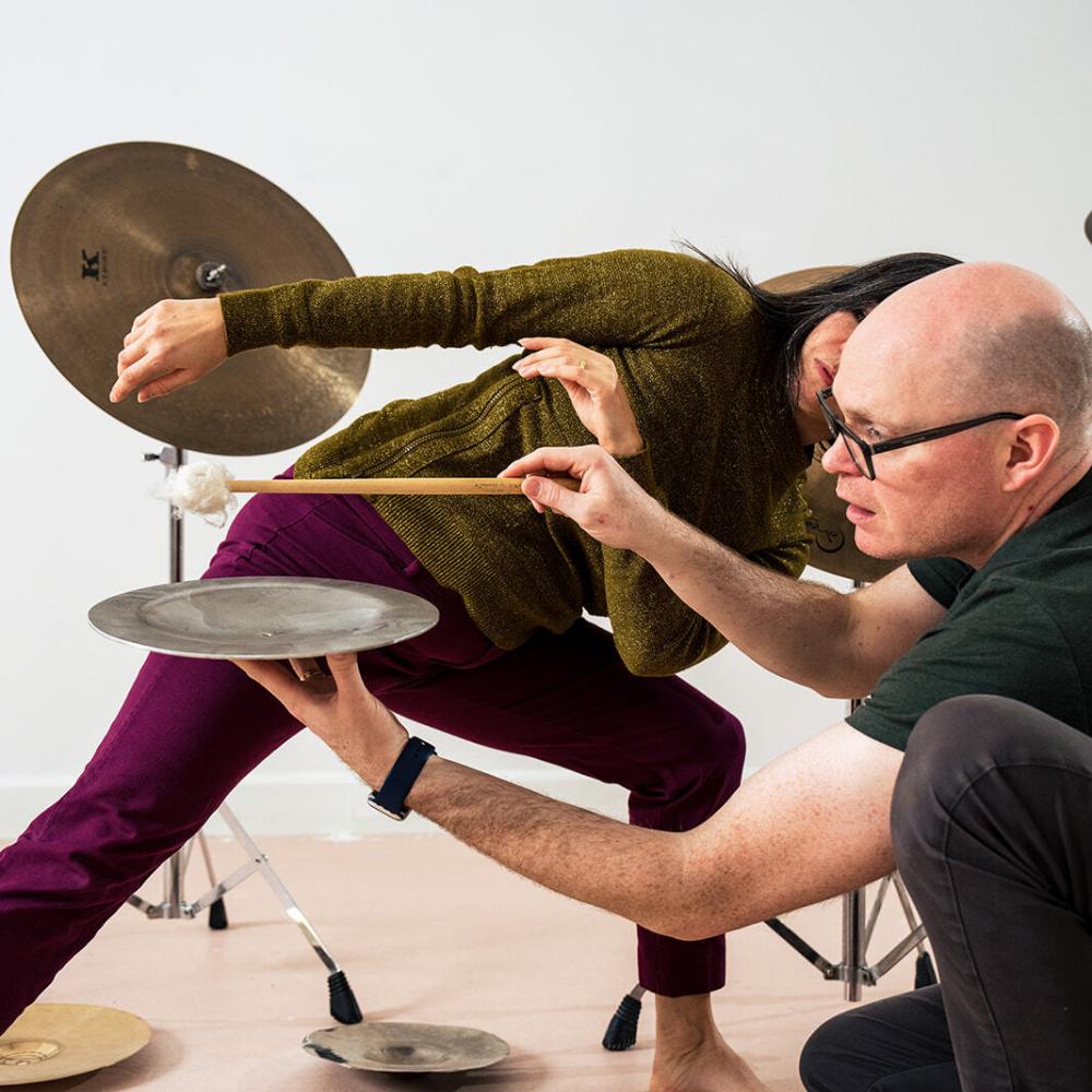 Two people move together with multiple cymbals