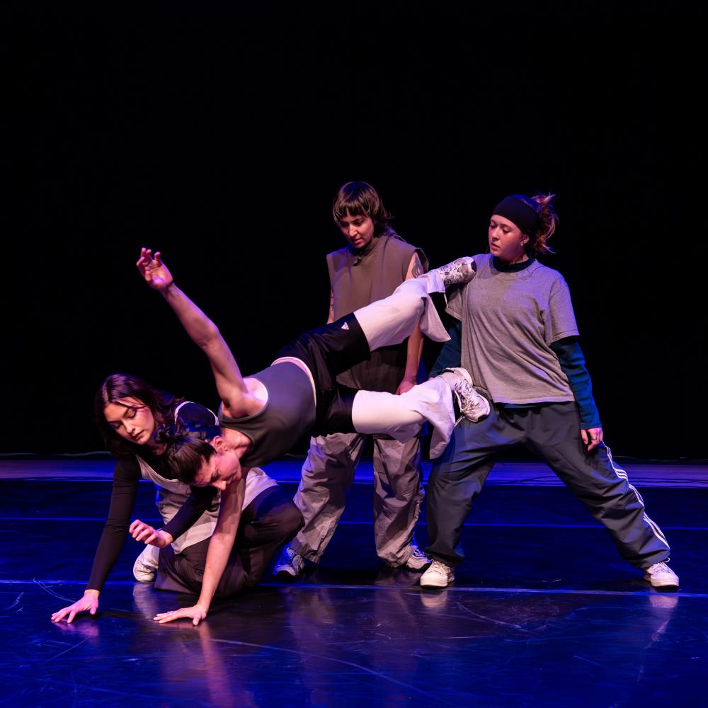 Three white dancers are helping a fourth balance in the air